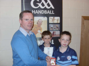 Tiernan receiving his medal from Chris Curran,  also pictured is Cappaghs Nathan McRory